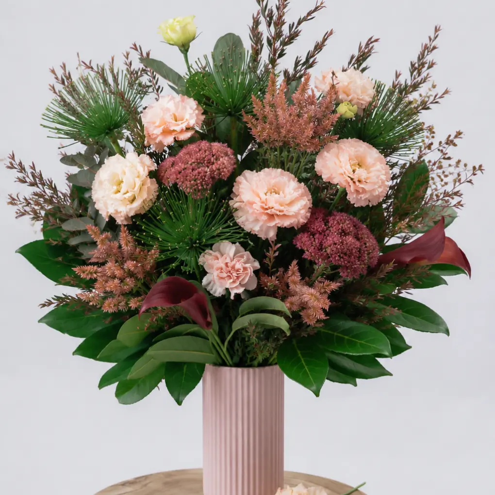 Contemporary blush vase flower arrangement with seasonal blooms, soft greenery and natural textures in a modern ceramic vase.