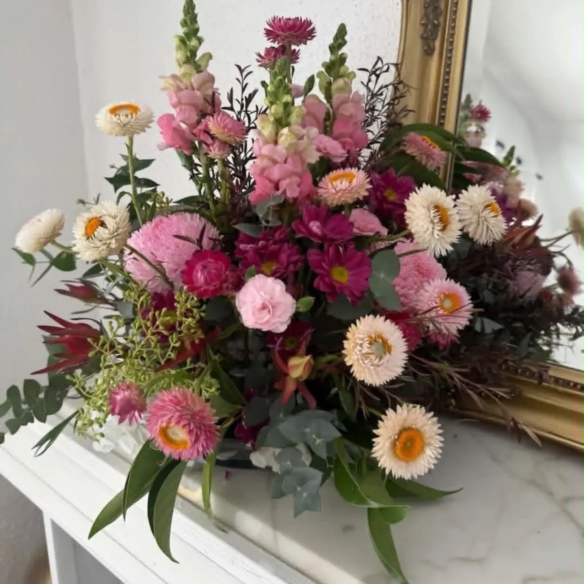 Seasonal corporate flower arrangement with pink and burgundy flowers styled for an office reception or business space.