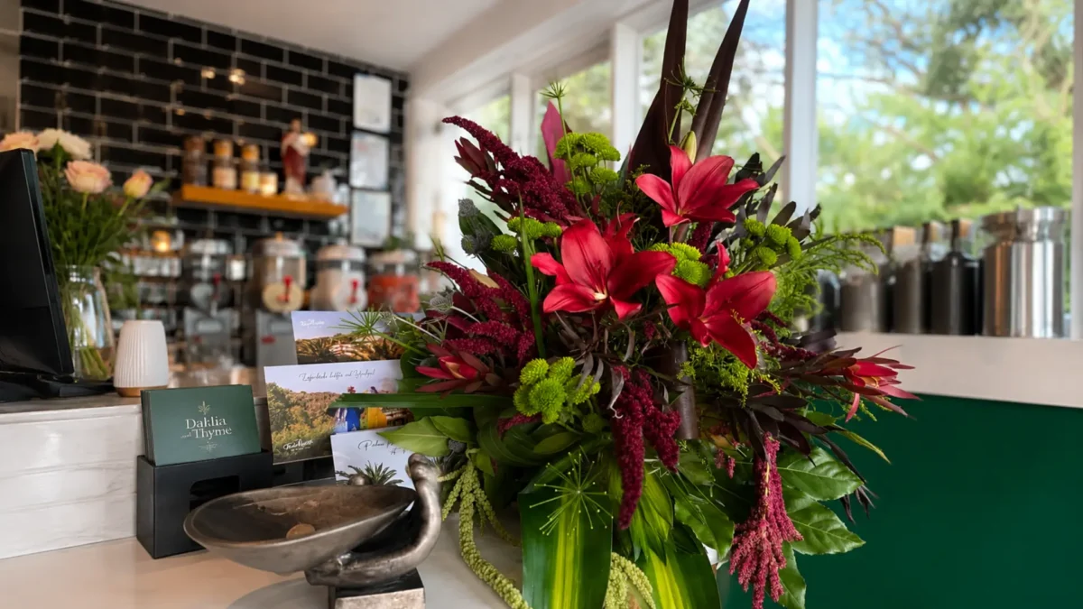 Bold reception flower arrangement featuring burgundy lilies, seasonal blooms and lush foliage displayed in a corporate or business space